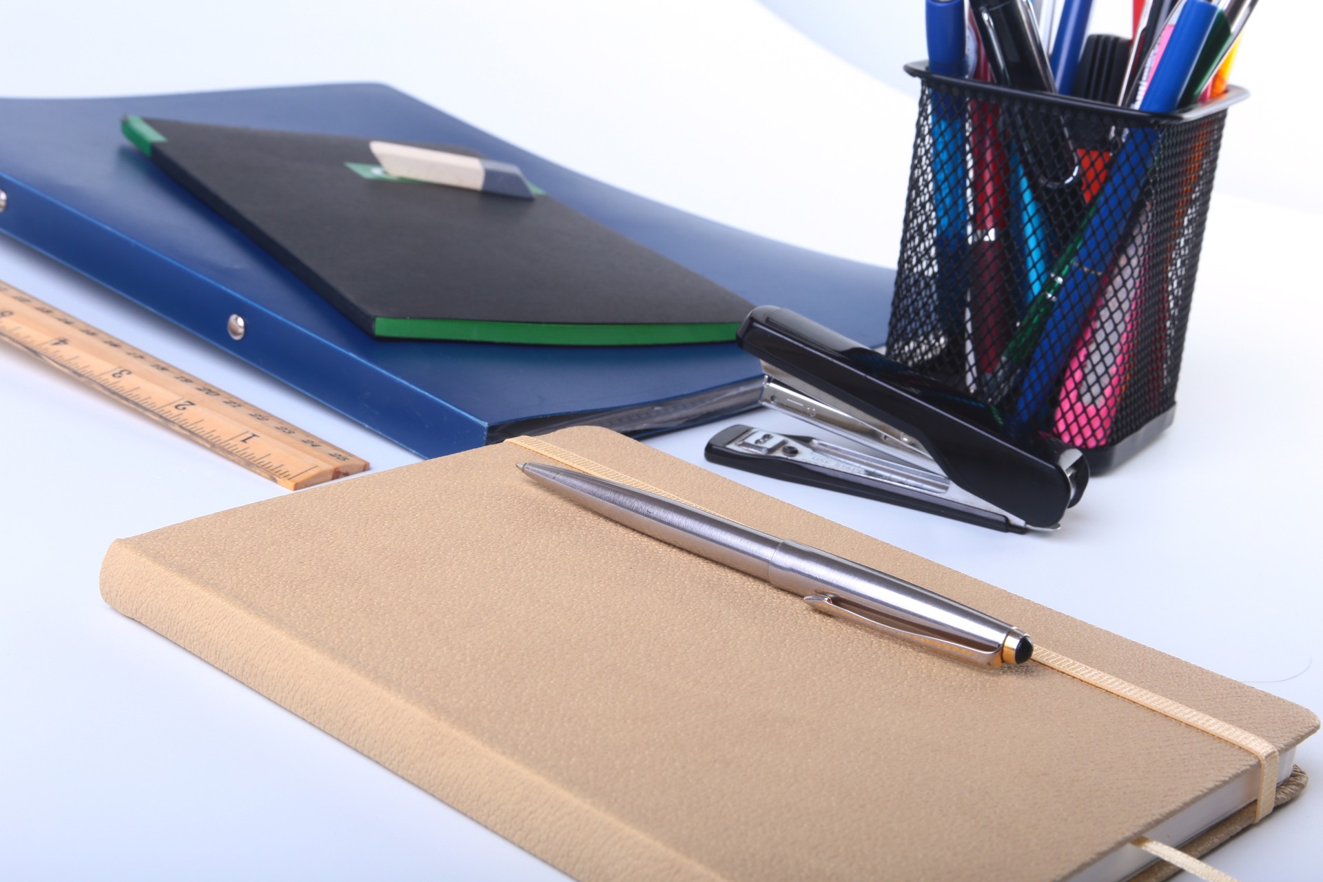 Colorful notebooks and office supplies on white table.